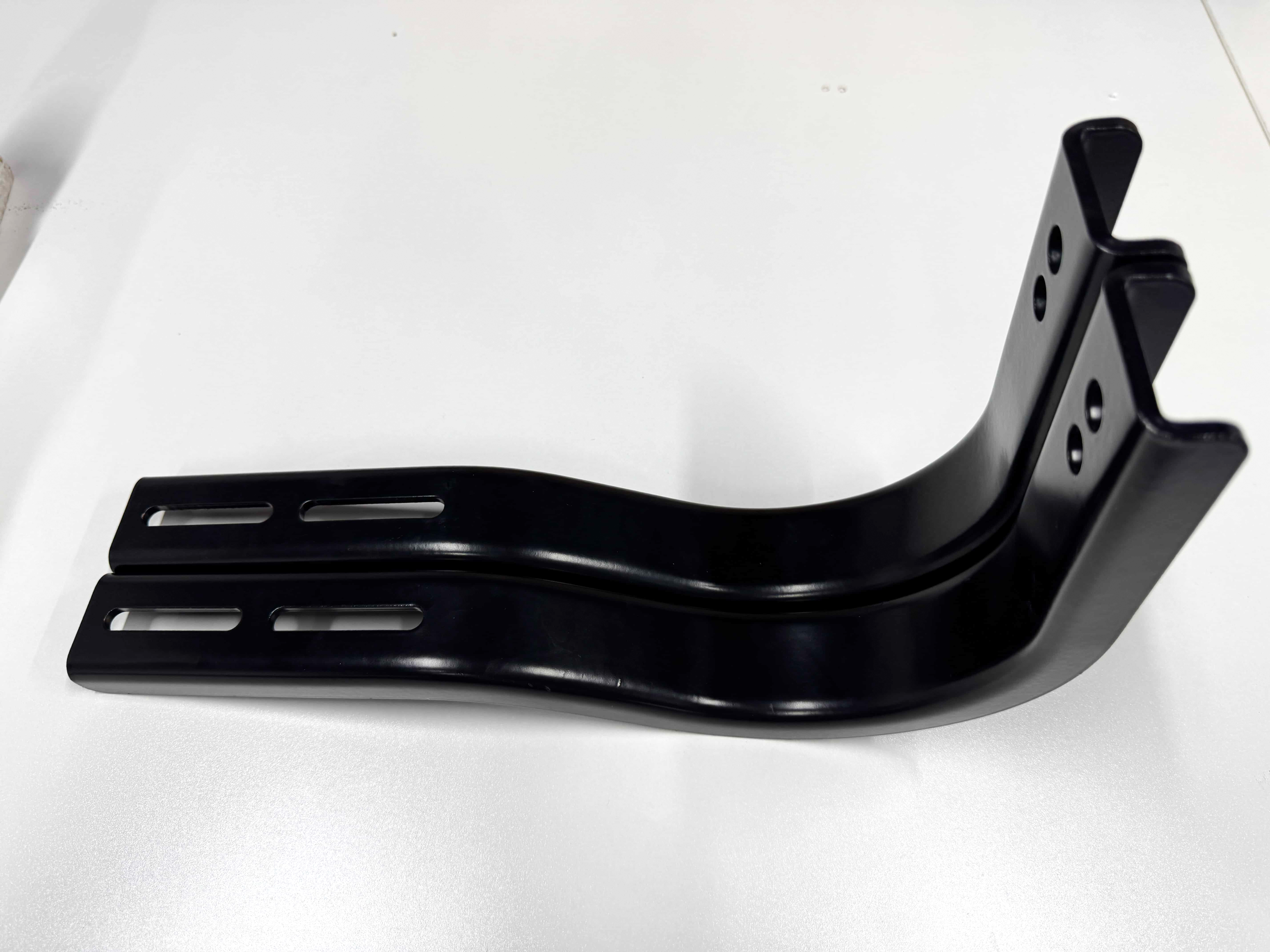 Black metal bracket with offset bends, elongated slots, and round mounting holes.
