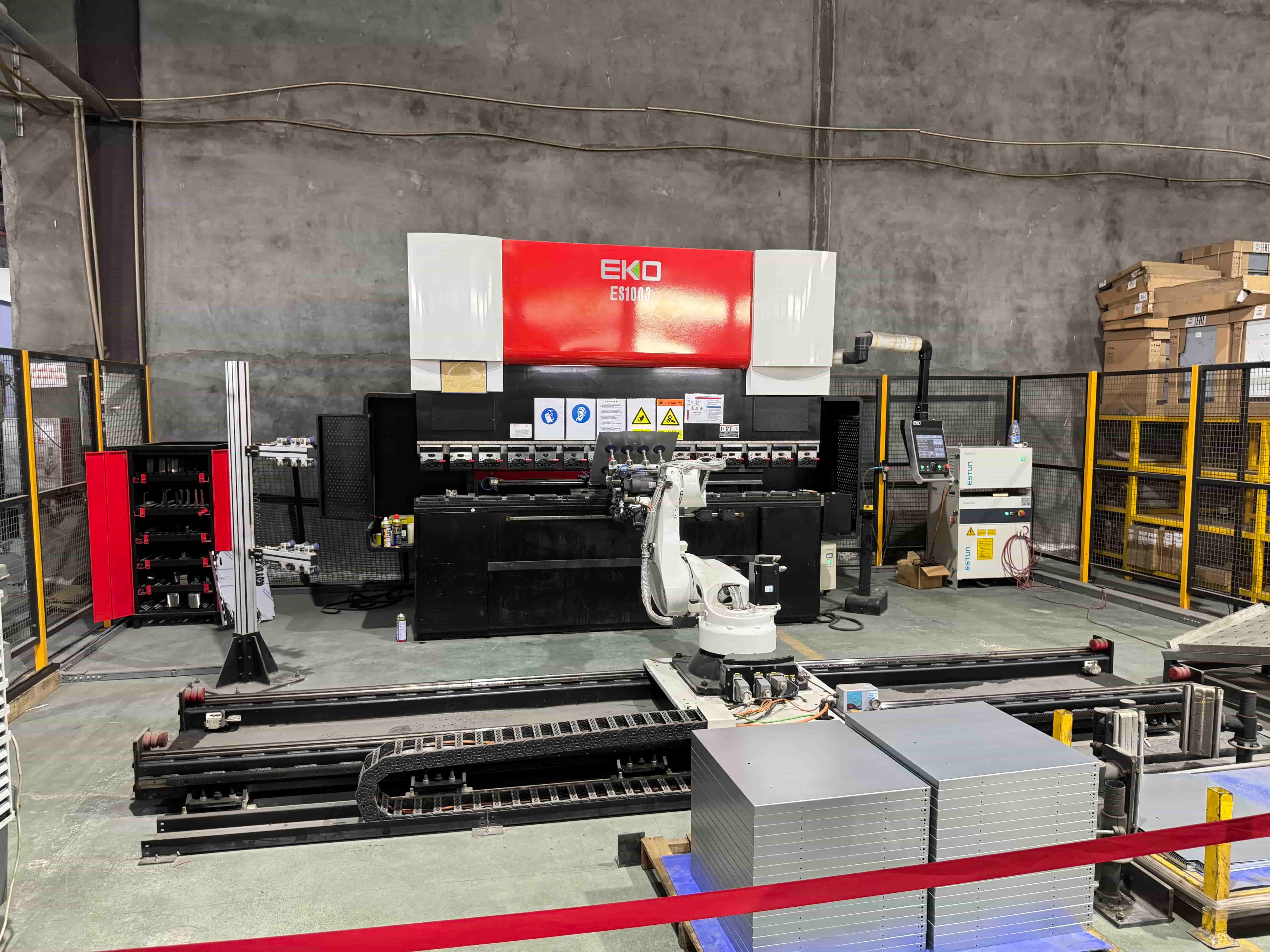 Industrial metalworking equipment with sheet material staged in a fabrication workspace.