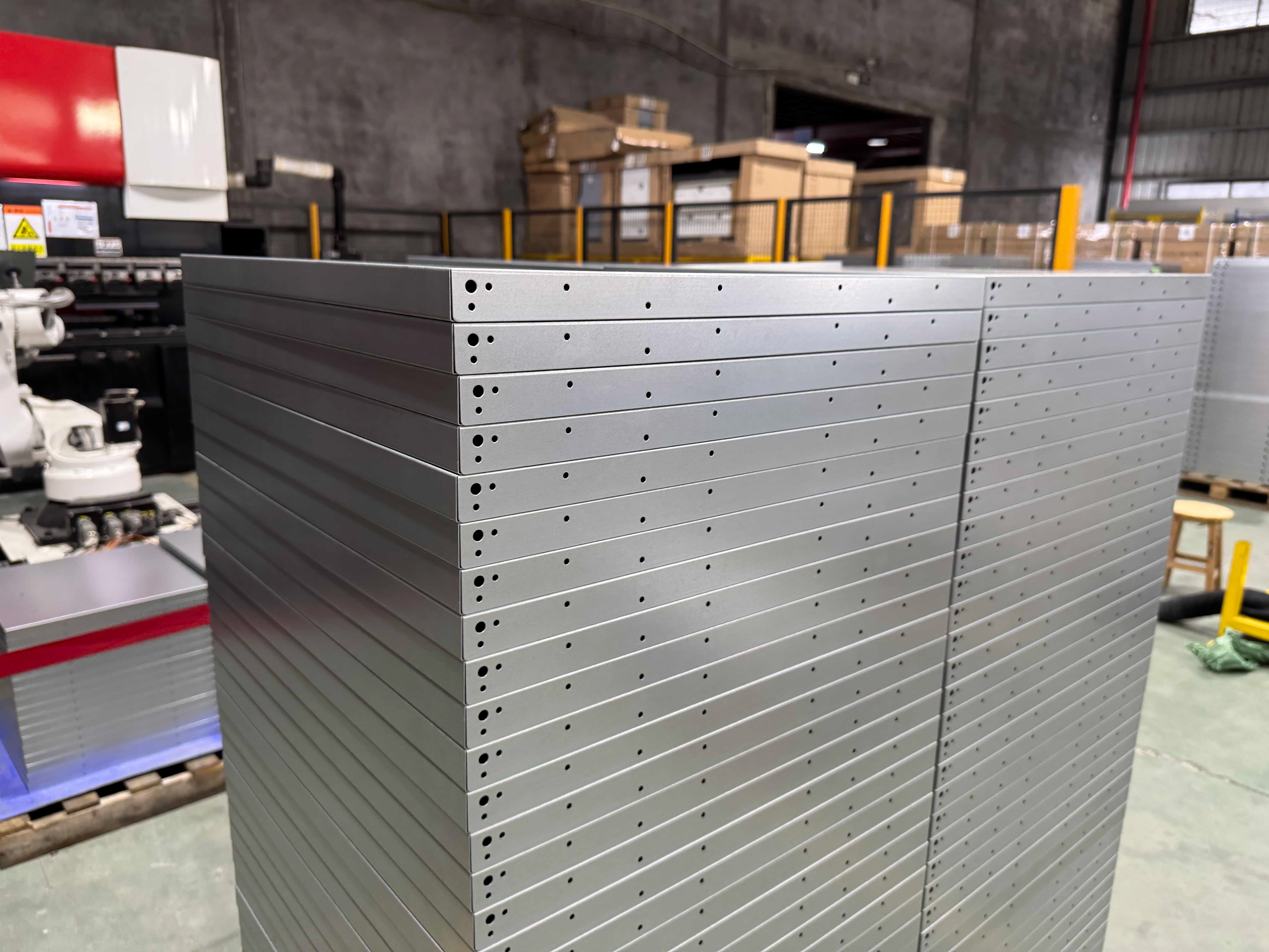 Stack of rectangular sheet metal panels with evenly spaced edge holes.