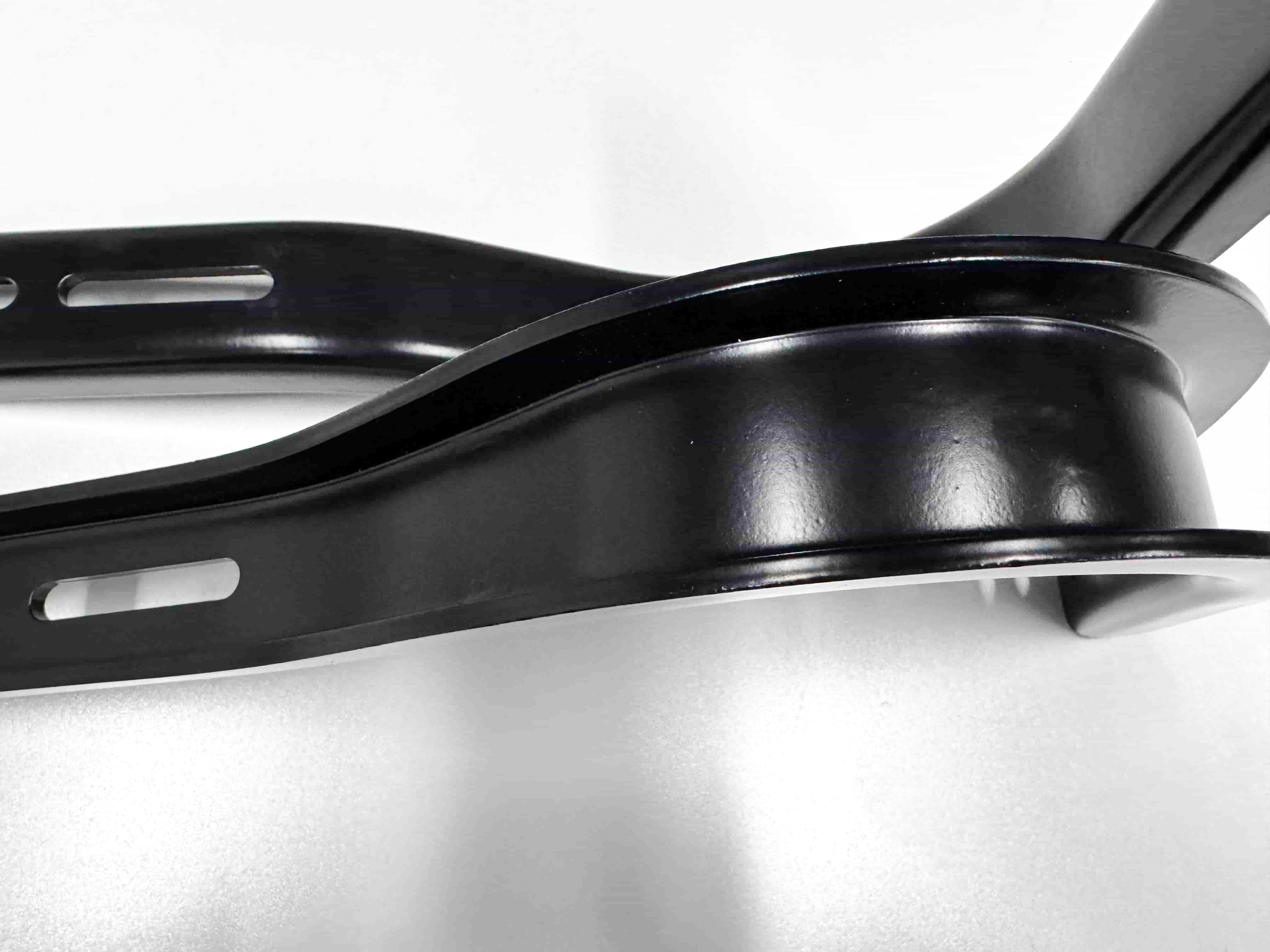 Close-up of black metal brackets with curved bends and elongated slots.