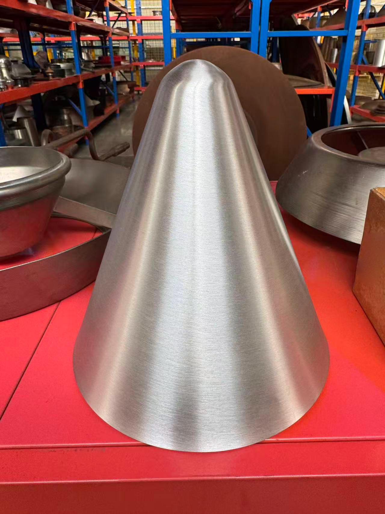 Silver metal cone with a narrow rounded top and wide circular base.