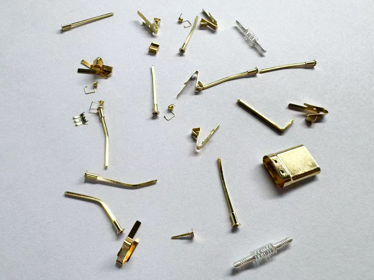 Assorted small metallic pins, electrical contacts, terminals, and formed parts.
