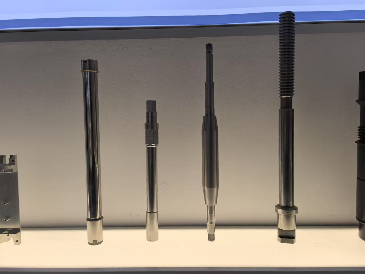Four upright metal shafts of varying lengths, including one with a long threaded section.