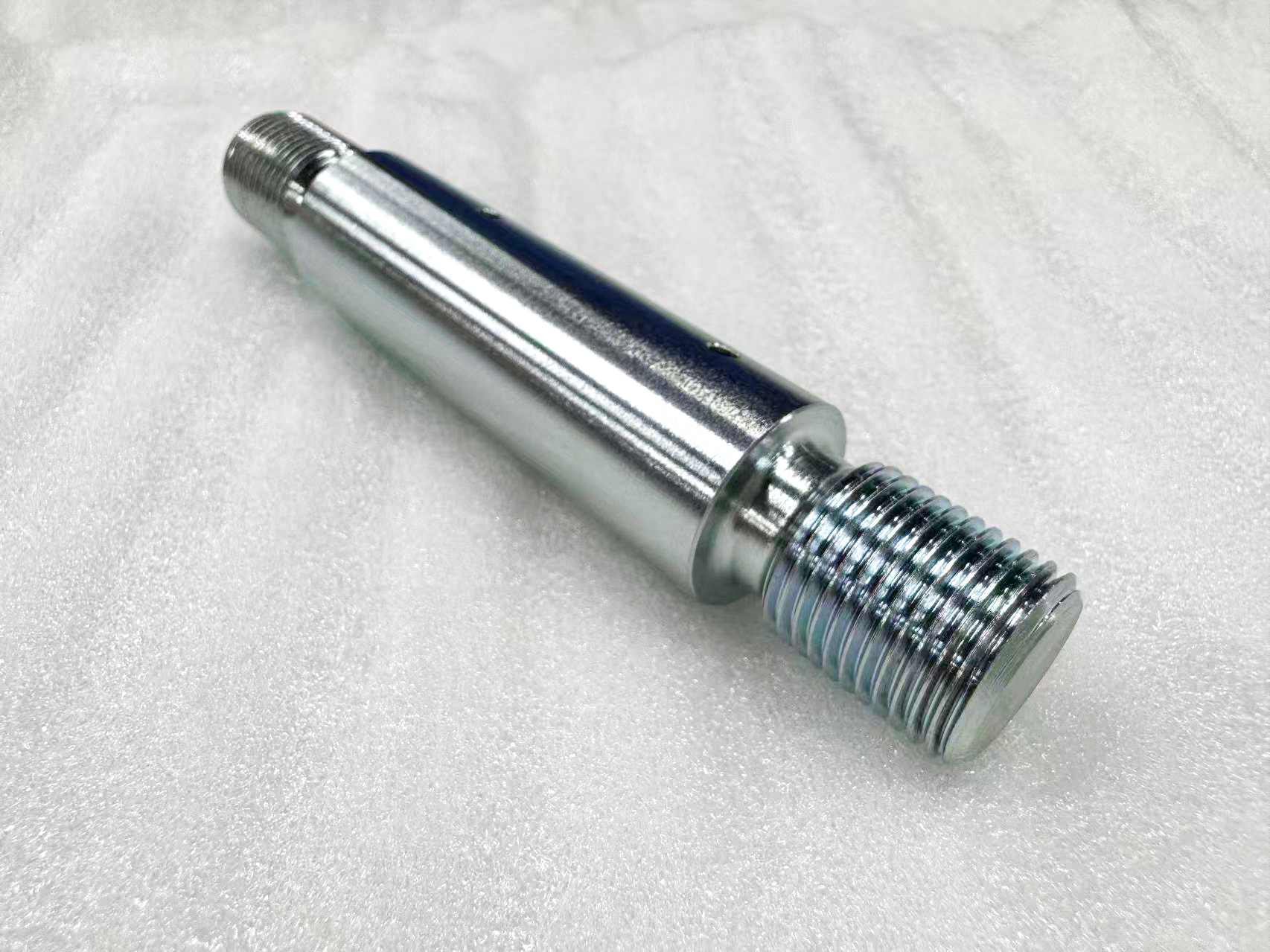 Polished cylindrical metal shaft with a stepped shoulder and external end threads.